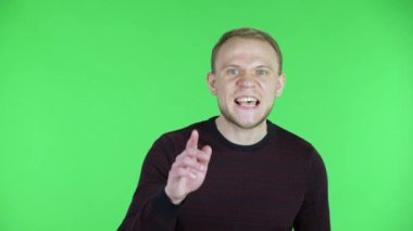 Orta yaşlı bir adamın portresi kameraya bakıyor ve sessiz bir jest yapıyor. Siyah kırmızı kazaklı traşsız bir erkek stüdyoda yeşil ekranda poz veriyor. Kapat..