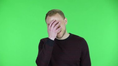 Orta yaşlı bir adamın portresi. Aman Tanrım, çok üzgün. Siyah kırmızı kazaklı traşsız bir erkek stüdyoda yeşil ekranda poz veriyor. Kapat..