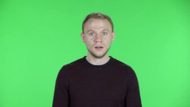 Orta yaşlı bir adamın portresi öfkeli ve sinirli biriyle konuşuyor. Siyah kırmızı kazaklı traşsız bir erkek stüdyoda yeşil ekranda poz veriyor. Kapat..