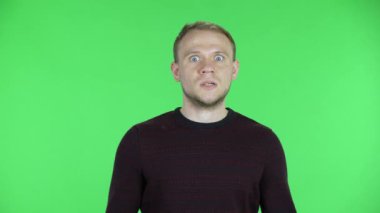 Orta yaşlı bir adamın portresi bekliyor, üzgün ve kızgın. Siyah kırmızı kazaklı traşsız bir erkek stüdyoda yeşil ekranda poz veriyor. Kapat..