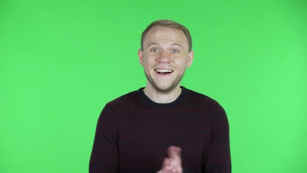 Retrato de un hombre de mediana edad aplaudiendo con alegría y deleite. Hombre sin afeitar en un suéter rojo negro posando en una pantalla verde en el estudio. De cerca.. — Vídeos de Stock