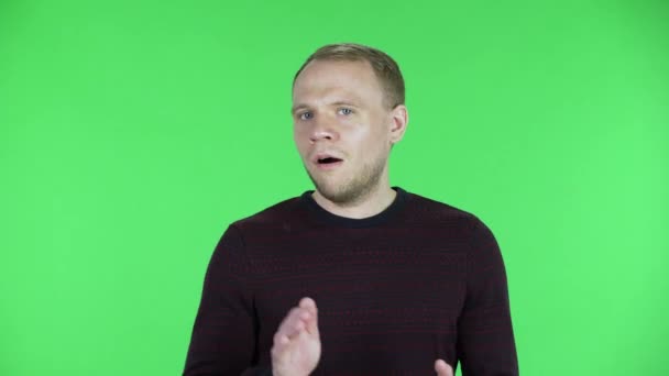 Ritratto di un uomo di mezza età che applaude, sbadiglia, noioso, poco interessante. Maschio non rasato in un maglione rosso nero in posa su uno schermo verde in studio. Da vicino.. — Video Stock