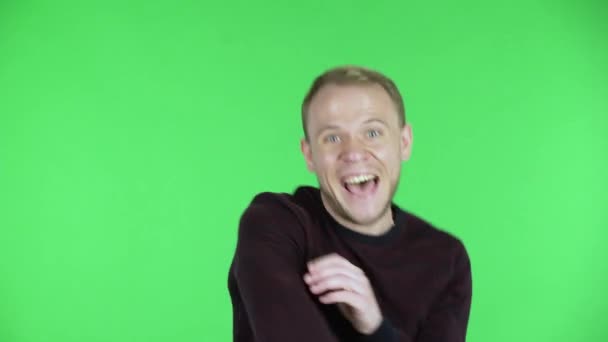 Portrett av en middelaldrende mann som ser inn i kameraet med spenning, for så å feire seierstriumfen sin. Ubarbert mann i svart rød genser som poserer på en grønn skjerm i studioet. Lukk. – stockvideo