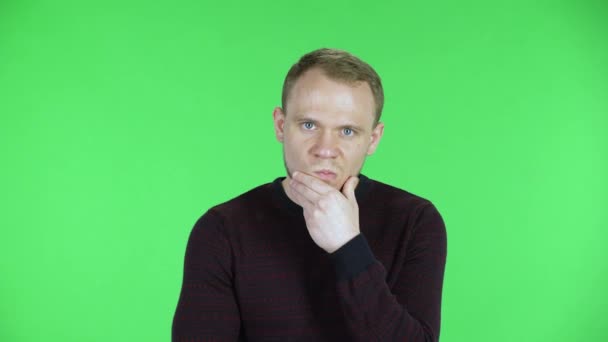 Portrait d'un homme d'âge moyen écoute l'information, regardant la caméra, en colère et très contrarié. Homme non rasé dans un pull noir rouge posant sur un écran vert en studio. Gros plan. — Video