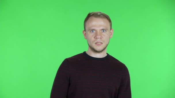 Портрет мужчины средних лет, смотрящего в камеру с шокированным и испуганным выражением лица. Небритый мужчина в черном красном свитере позирует на зеленом экране в студии. Закрыть. — стоковое видео
