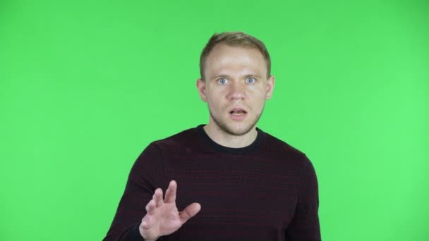 Portret mężczyzny w średnim wieku patrzącego w kamerę ze wstrząśniętym i przerażonym wyrazem twarzy. Nieogolony mężczyzna w czarnym czerwonym swetrze, pozujący na zielonym ekranie w studio. Zamknij się.. — Wideo stockowe