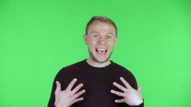 Orta yaşlı bir adamın portresi masum bir şekilde kendini işaret ediyor, kim olduğumu söylüyor, ben değilim. Siyah kırmızı kazaklı traşsız bir erkek stüdyoda yeşil ekranda poz veriyor. Kapat..