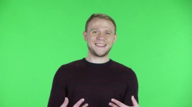 Orta yaşlı bir adamın portresi masum bir şekilde kendini işaret ediyor, kim olduğumu söylüyor, ben değilim. Siyah kırmızı kazaklı traşsız bir erkek stüdyoda yeşil ekranda poz veriyor. Kapat..