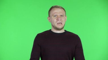 Orta yaşlı bir adamın portresi. Yüksek sıcaklıklarda serinleyen bir adamın portresi. Siyah kırmızı kazaklı traşsız bir erkek stüdyoda yeşil ekranda poz veriyor. Kapat..