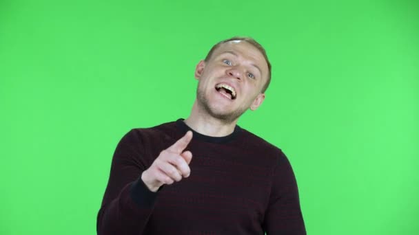 Retrato de un hombre de mediana edad escucha atentamente, asiente con la cabeza con aprobación, señala un dedo sí, tienes razón, seguro. Hombre sin afeitar en suéter posando en una pantalla verde en el estudio. De cerca.. — Vídeo de stock