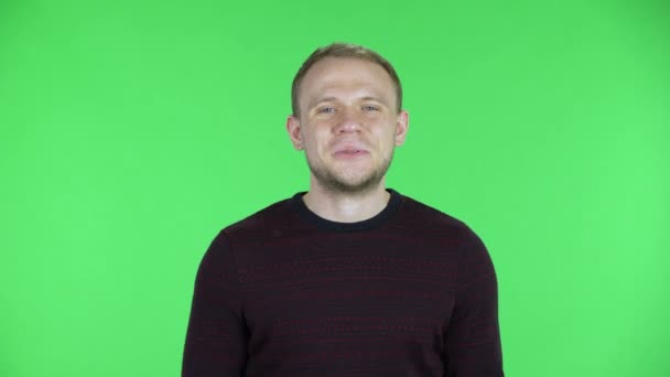 Porträtt av en medelålders man som håller ihop handflatan och ber om något. Orakad man i svart röd tröja som poserar på en grön skärm i studion. Närbild. — Stockvideo