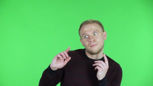 Portrait of a middle aged men points fingers to the side, copying space. Unshaven male in a black red sweater posing on a green screen in the studio. Close up. — Stock Video