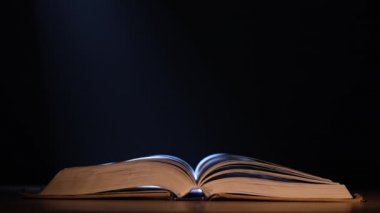 Karanlık bir stüdyoda, açık bir kitap, siyah bir arkaplanda, bir ışık huzmesi, onu aydınlatır. Kitabın dumanın ve kar yağışının ortasında yavaş çekimde nefes kesici bir görünüm. Kapat..
