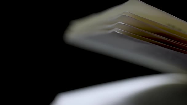 Scrollen door wazige boekpagina 's in slow motion. Open boek op een zwarte achtergrond. Sluiten.. — Stockvideo