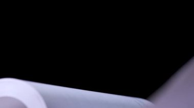 Stüdyoda siyah arka plan üzerine açık bir kitap. Daktiloyla yazılmış beyaz sayfalar yavaş çekimde çevriliyor. Öğrenme ve eğitim kavramı. Kapat..