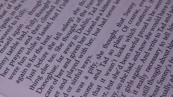 Libro abierto con texto en inglés de cerca. Mientras lee el libro, la chica corre su dedo índice a lo largo de las líneas. Concepto de lectura y literatura. Movimiento lento. — Vídeos de Stock