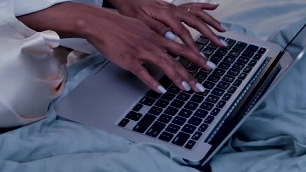 흑인 여성 이 노트북 컴퓨터 키보드로 타자를 치고 있습니다. 여자들은 원격 작업, 소셜 네트 워킹, 원격 학습을 위해 침실에서 랩탑을 사용 합니다. 느린 동작으로 가까이 붙어 있는 손가락 과 키를 만지작 거리는 손가락 — 비디오