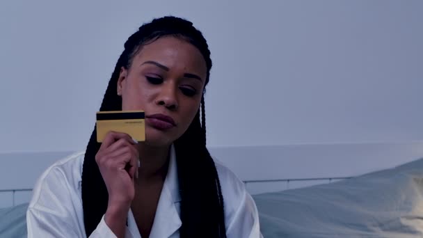 Pretty African American žena dělá on-line nákup pomocí kreditní karty. Černá žena pózuje v ložnici v pyžamu. Lehký interiér pokoje. Zavřít. Zpomalený pohyb. — Stock video
