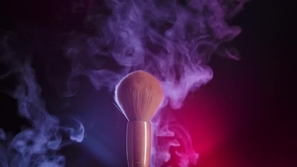 İki makyaj fırçası birbirine dokunarak karmaşık bir kozmetik toz zerresi oluşturur. Parlak neon ışıkta karanlık bir stüdyoda makyaj fırçalarını kapatın. Yavaş çekim. — Stok video