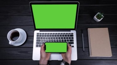 Kız çeşitli cihazlar, dizüstü bilgisayarlar ve akıllı telefonlar kullanıyor. Yeşil ekranlı bir dizüstü bilgisayar ve elinde tuttuğu yeşil ekranlı bir telefon. Ağır çekim. Kapat..