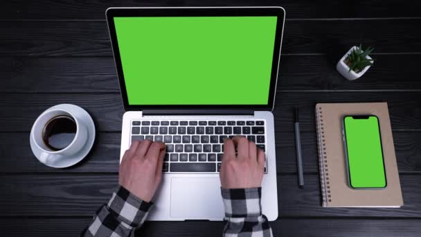 Женские руки печатают на клавиатуре ноутбука с зеленым экраном и хромированной клавишей. На столе рядом с ноутбуком находится смартфон с зеленым экраном и хромированным ключом. Медленное движение. Закрыть. — стоковое видео