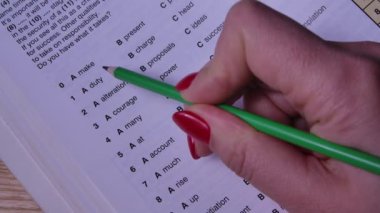 Bir kadın İngilizce bir kitap okuyor. Kız testlere cevap veriyor, cevapları kalemle işaretliyor. Eğitim konsepti. Ağır çekim. Kapat..