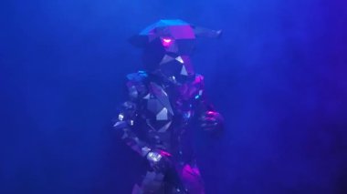 Aynalardan parlayan gümüş kostümlü dansçılar dumanlı stüdyo arka planında boynuzlu boğa şeklinde. Dans eden aktörler ve neon mavisi pembe ışıkta neşeyle sergilenen gösteriler. Kapatın. Yavaş çekim.