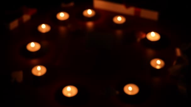 Fundo de crepúsculo borrado com velas ardentes, presentes e corações decorativos em uma mesa vermelha. Detalhes da decoração. Noite romântica. Conceito do Dia dos Namorados. Fecha. Movimento lento. — Vídeo de Stock