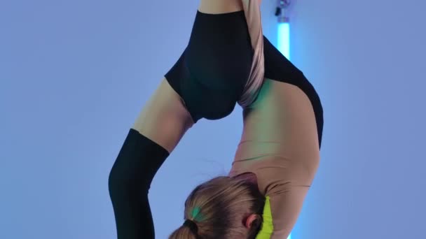 Ginnasta di equilibrio allungata e rotante su seta ariosa. Giovane ragazza in body nero esegue elementi acrobatici in studio sullo sfondo di luci al neon luminose. Chiudete. Rallentatore. — Video Stock