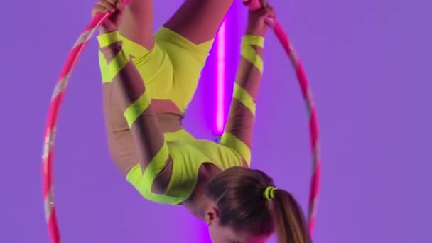 Mladý letecký gymnastik provádí akrobatické kousky na vzduchovém koši. Vzrušující akrobatické představení v podání dospívající dívky na pozadí jasných neonových světel. Zavřít. Zpomalený pohyb. — Stock video