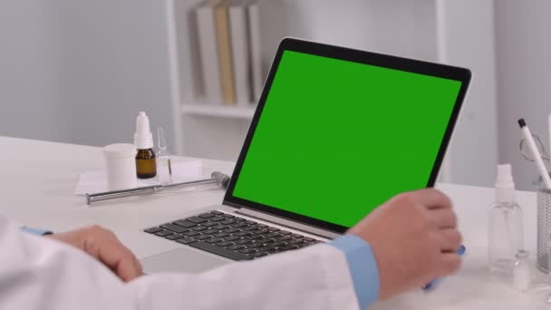 Male doctor consults patient using laptop with green screen chroma key and demonstrates vial with vaccine. Remote online consultation about need for vaccination. Telemedicine. Close up. Slow motion. — Vídeos de Stock