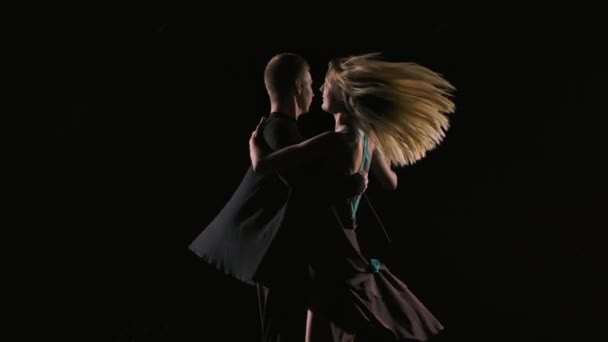 Pár tanečníků tančí ve tmě na pozadí černého studia. Muž a žena tančí smyslný tanec na vodní hladině a vytvářejí šplouchání. Zpomal. Zavřít. — Stock video