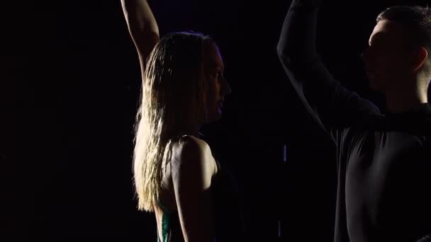 Η σιλουέτα ενός ζευγαριού χορευτών που παίζουν ένα στοιχείο από το λατίνο bachata χορού σε μαύρο φόντο στούντιο. Ένας άντρας και μια γυναίκα χορεύουν έναν αισθησιακό χορό στη βροχή. Αργή κίνηση. Κλείσε. — Αρχείο Βίντεο