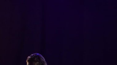 İnce bir sarışın yağmur damlaları ve su arasında bachata yapıyor. Kısa elbiseli tutkulu bir kadın, siyah bir stüdyo arka planında mavi ışıkla performans sergiliyor. Ağır çekim. Kapat..
