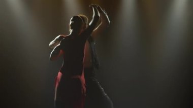 Bir çift balo dansçısı tarafından yapılan tutkulu bir tango dansı. Karanlık bir stüdyoda parlak ışıklarla Latin dansı yapan şık bir kadın ve erkek. Siluetler. Kapat..