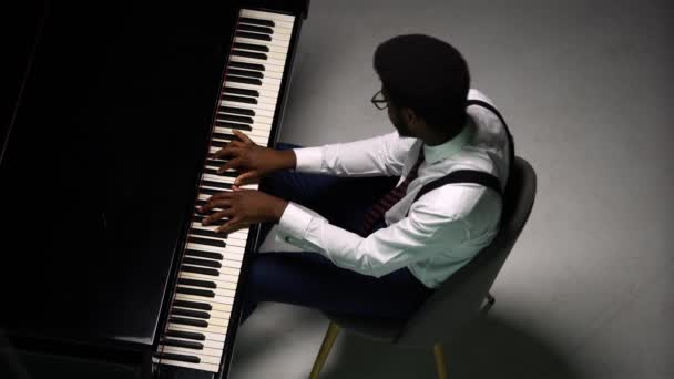 グランドピアノを演奏スタイリッシュな男のトップビュー。アフリカ系アメリカ人は、彼の指で黒と白のキーに触れ、メロディーのリズムを作り出します。黒人男性ピアニストのクローズアップ. — ストック動画