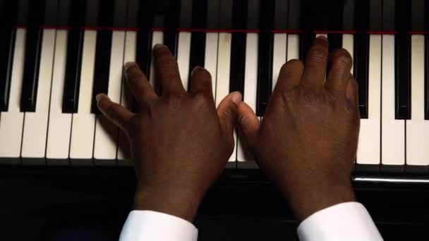 Ovanifrån av manliga händer spelar flygeln. Den afroamerikanska vidrör de svarta och vita tangenterna med fingrarna för att skapa rytmen i melodin. Närbild svarta händer av en manlig pianist. — Stockvideo