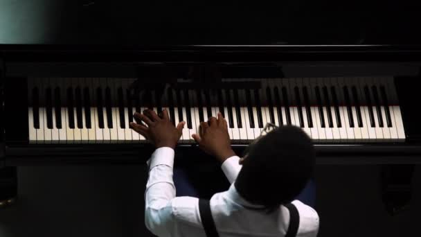 Top kilátás elegáns férfi játszik nagy zongora. Az afro-amerikai megérinti a fekete-fehér billentyűket az ujjaival, hogy megteremtse a dallam ritmusát. Közelről egy fekete férfi zongorista. — Stock videók
