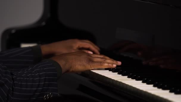 A férfi kezek oldalnézete, ahogy zongoráznak. Az afro-amerikai megérinti a fekete-fehér billentyűket az ujjaival, hogy megteremtse a dallam ritmusát. Közelről egy férfi zongorista fekete kezei. — Stock videók