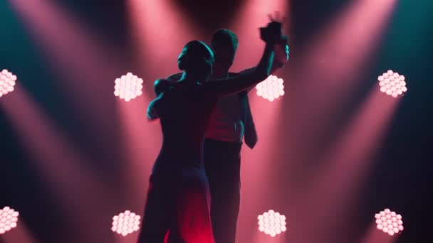 Anmutiger argentinischer Tango zwischen Rauch und knallrotem Neonlicht in einem dunklen Studio. Tanzshow mit leidenschaftlichen Tanzpartnern. Silhouetten. Nahaufnahme. — Stockvideo