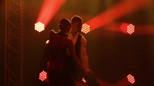 Anmutiger argentinischer Tango zwischen Rauch und knallrotem Neonlicht in einem dunklen Studio. Tanzshow mit leidenschaftlichen Tanzpartnern. Silhouetten. Nahaufnahme. — Stockvideo