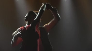 Bir çift balo dansçısı tarafından yapılan tutkulu bir tango dansı. Karanlık bir stüdyoda parlak ışıklarla Latin dansı yapan şık bir kadın ve erkek. Siluetler. Kapatın. Yavaş çekim.