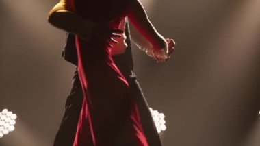 Bir çift balo dansçısı tarafından yapılan tutkulu bir tango dansı. Karanlık bir stüdyoda parlak ışıklarla Latin dansı yapan şık bir kadın ve erkek. Siluetler. Kapatın. Yavaş çekim.