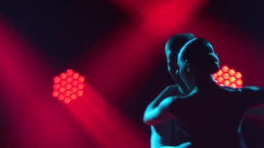 Duman arasında zarif Arjantin tangosu ve karanlık bir stüdyoda parlak kırmızı neon ışıklar. Tutkulu dans partnerleri tarafından yapılan dans gösterisi. Siluetler. Kapatın. Yavaş çekim.