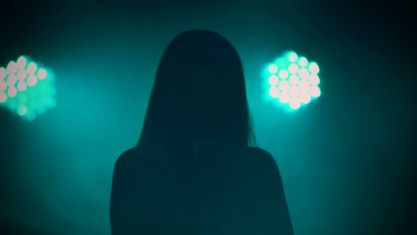 Σκούρα σιλουέτα μιας γυναίκας σολίστ που τραγουδάει σε ένα ρετρό μικρόφωνο σε μαύρο φόντο στούντιο με φωτεινά φώτα. Ο ποπ σταρ παίζει ζωντανά σε ένα εορταστικό πάρτι. Κλείσε.. — Αρχείο Βίντεο