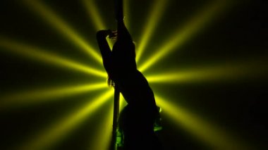 Genç ve egzotik dansçıların gölgelerinin alttaki görüntüsü. Karanlıkta, dönen sarı ışıkların arka planında dans ediyorlar. Direk dansı elementleri, kadınlar için fitness. Kapatın. Yavaş çekim.