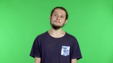Bir şeyi düşünen ya da hayal eden genç bir adamın portresi. Stüdyoda yeşil ekranda sakallı siyah saçlı bir adam. Kapat..