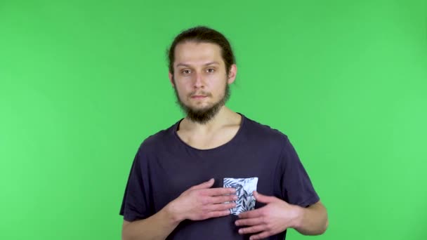 Portrait of a man on a green screen. A man puts his hands on his heart, describes with his hands the shape of a heart, blows a kiss and with a gesture of his hand catches a reciprocal one. Close up. — Stock Video