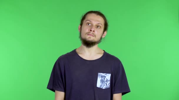 Porträtt av en ung man som tänker eller drömmer om något. En mörkhårig man med skägg i studion på en grön skärm. Närbild. — Stockvideo