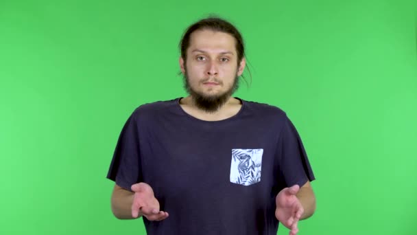 Portrait of a young man refusing stress and accepting the situation, calming down, breathing deeply. A darkhaired man with a beard in a black Tshirt in the studio on a green screen. Close up. — Stock Video